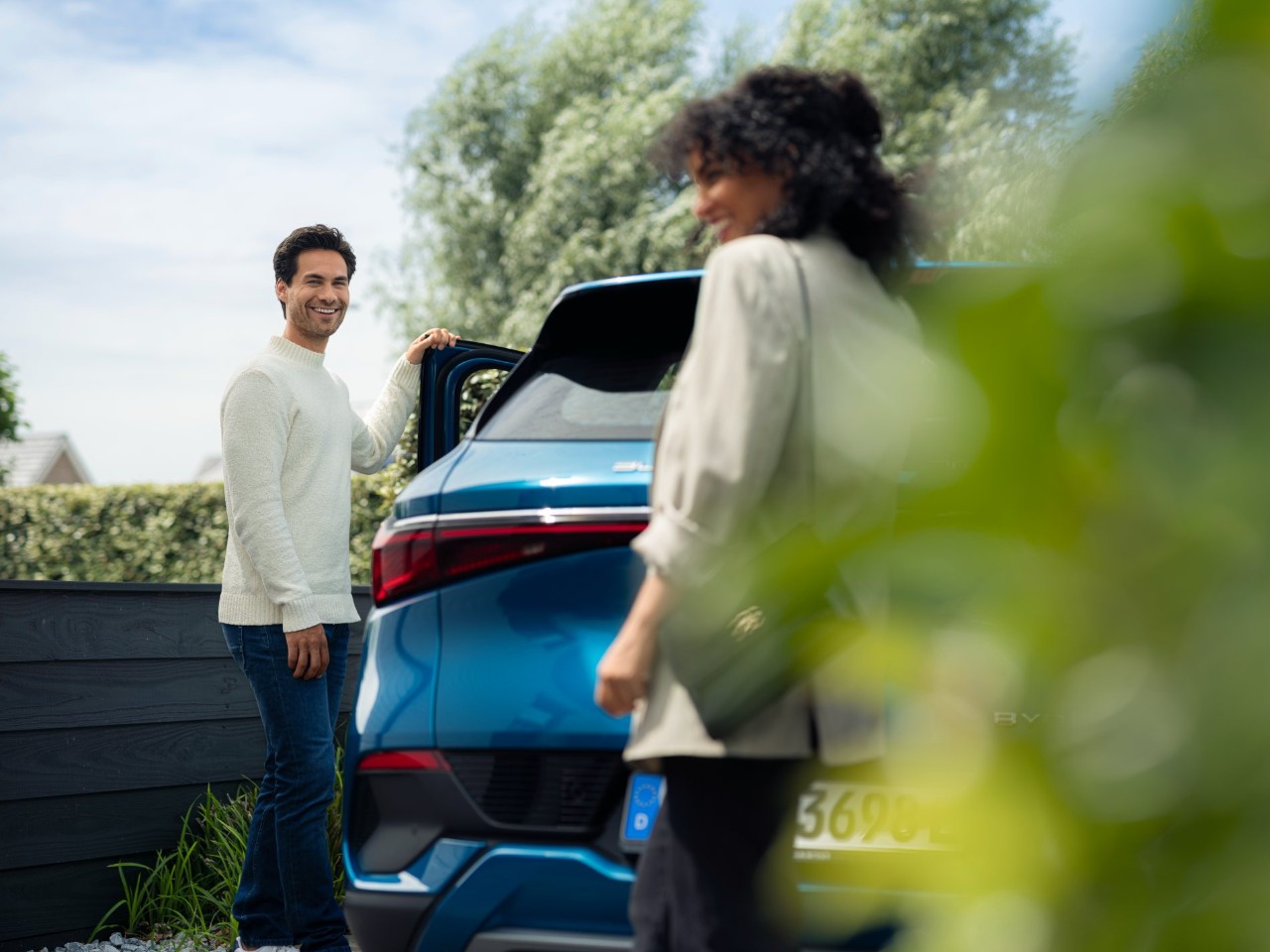 Man and a woman next to a blue car